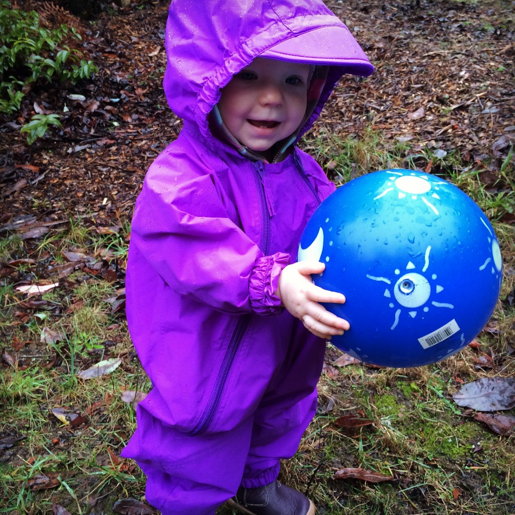toddler in rain suit with ball